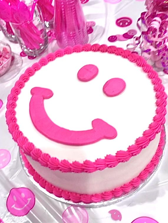 a pink and white cake with a smiley face on it