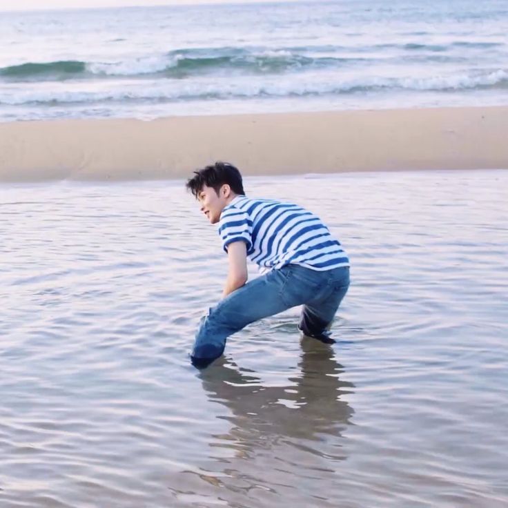 a man kneeling down in the water at the beach