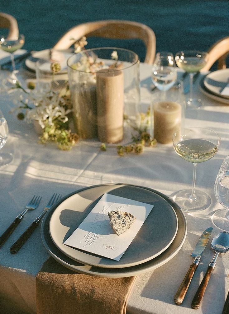 the table is set with plates, silverware and wine glasses for an elegant dinner