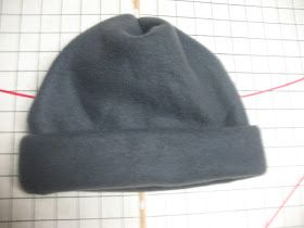 a gray hat sitting on top of a table next to a piece of red thread