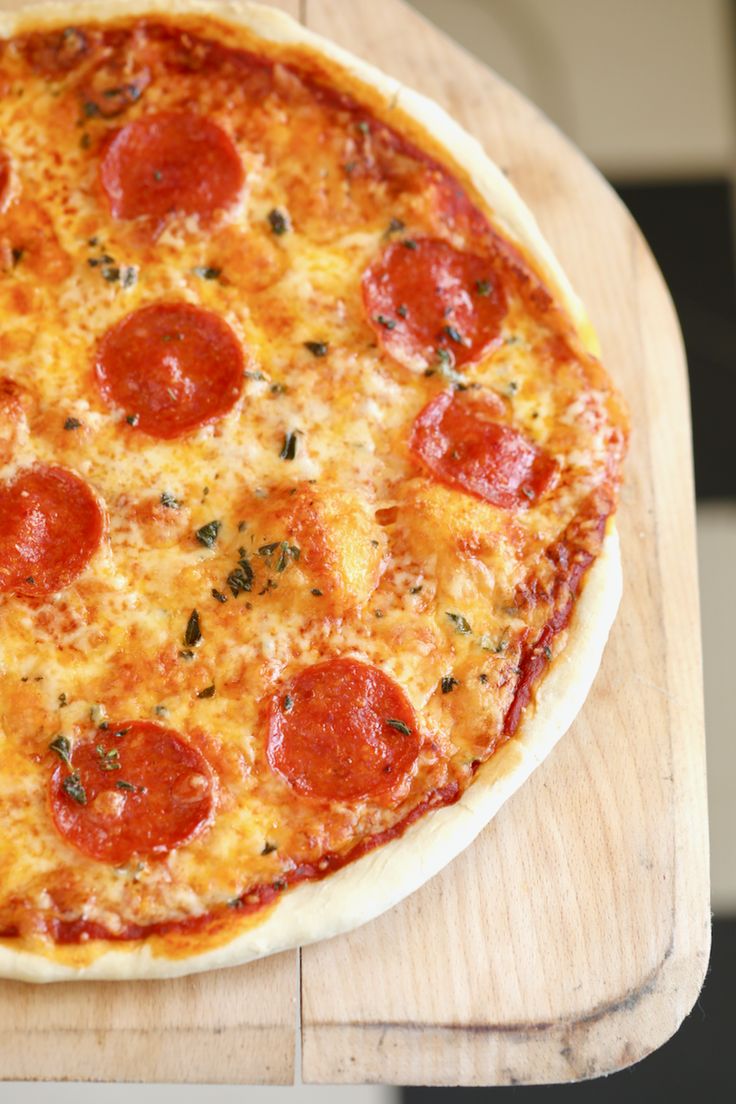 a pepperoni pizza sitting on top of a wooden cutting board