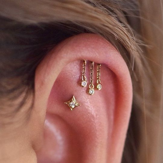 a close up of a person's ear with three different piercings on it