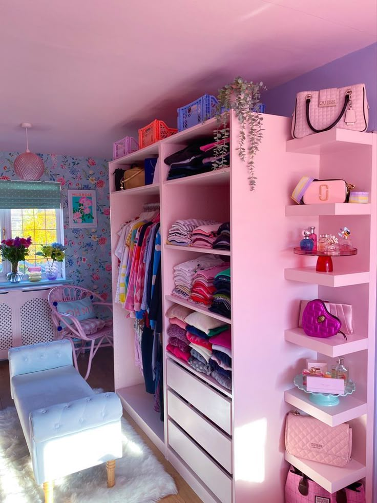 a room with pink walls and shelves filled with clothes, bags and purses on top of them