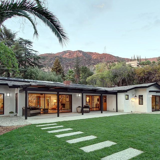 the house is surrounded by green grass and palm trees