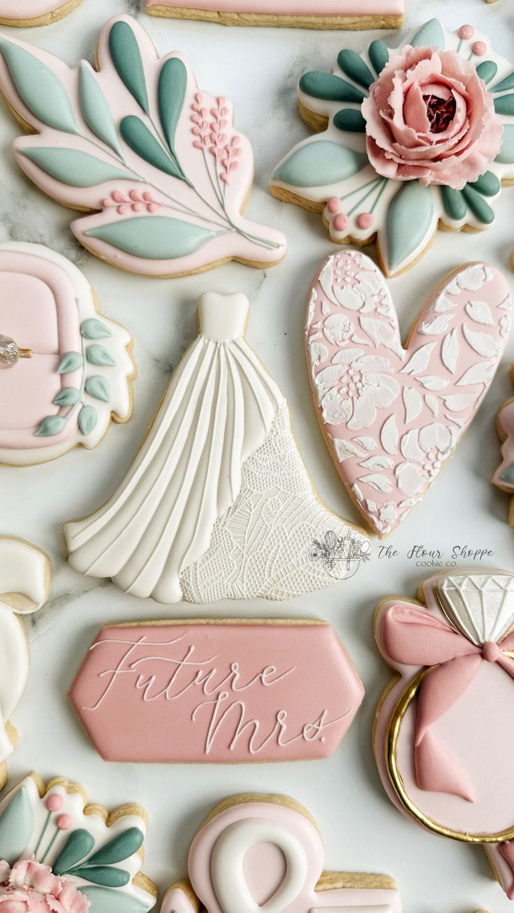 decorated cookies are arranged on top of a white tablecloth with pink and blue accents