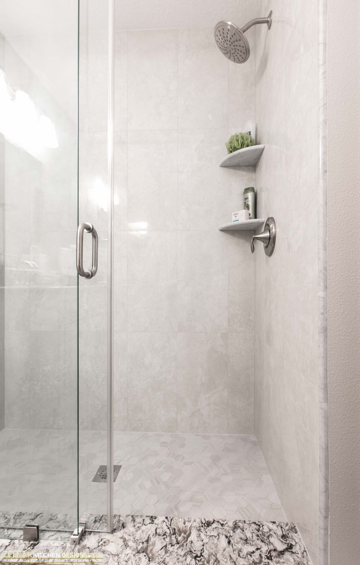 a walk in shower sitting next to a white wall with shelves on the side of it