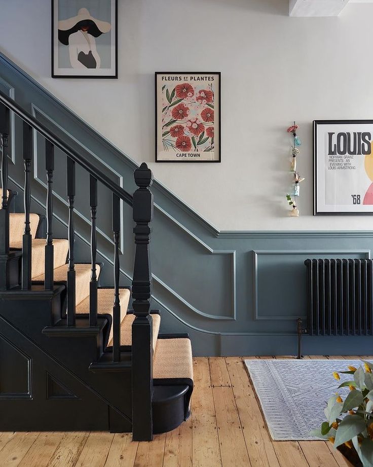 a staircase with pictures on the wall and wooden flooring in front of it, along with an area rug