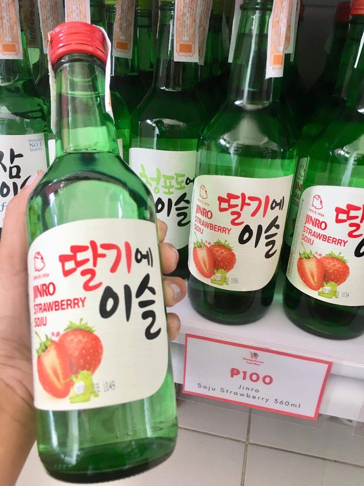 a person is holding up a bottle of strawberry soda in front of some other bottles