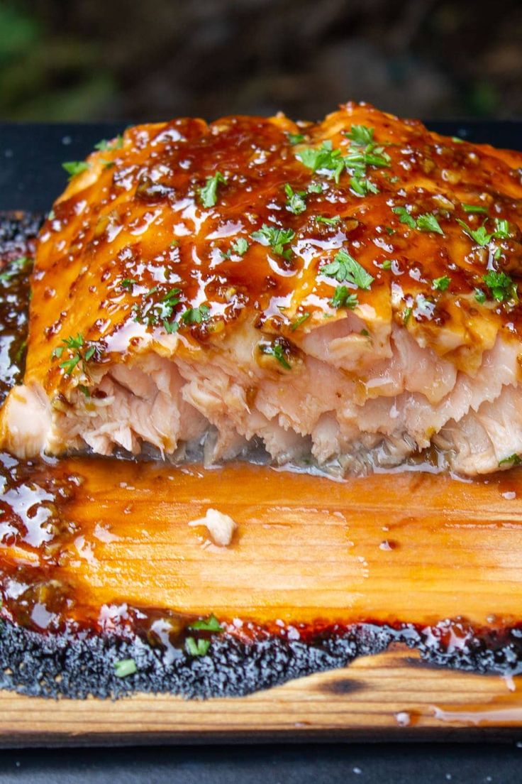 a piece of meat covered in sauce on top of a wooden cutting board with the words maple cedar plank salmon