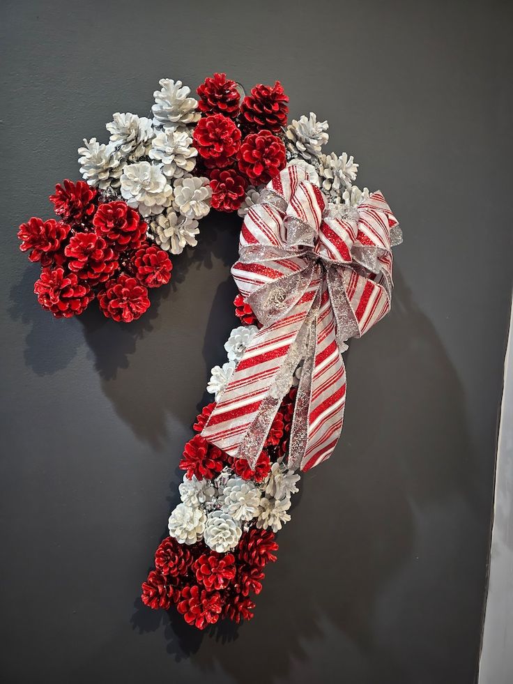 a christmas wreath with red and white flowers on the front, attached to a gray wall