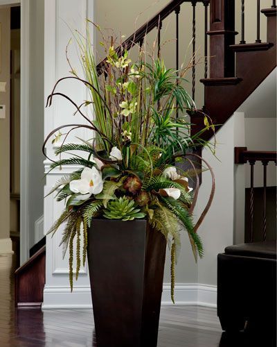 a vase filled with flowers sitting on top of a wooden floor next to a stair case