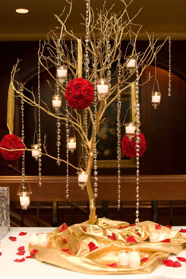 a decorated table with candles and flowers on it in front of a wall hanging from the ceiling