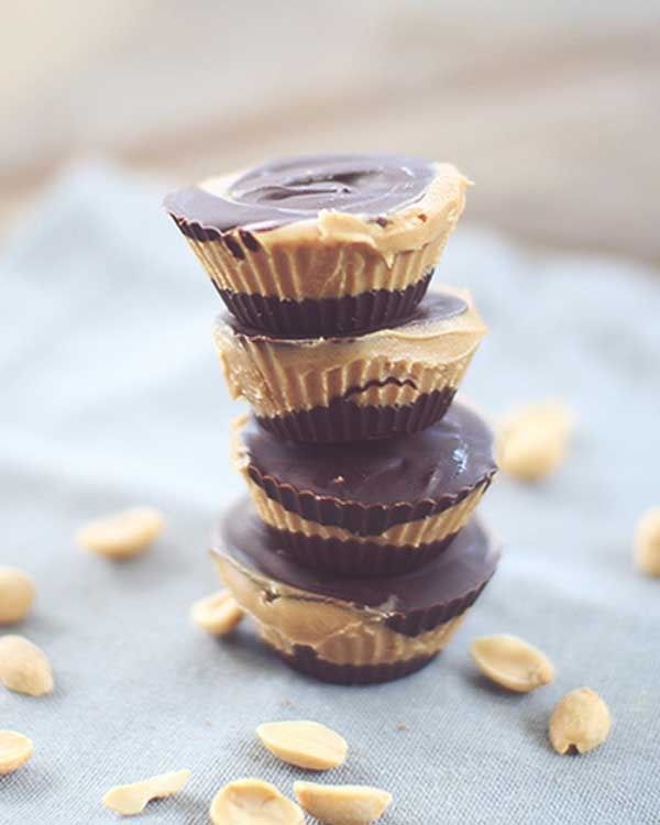 three chocolate peanut butter cups stacked on top of each other with peanuts scattered around them