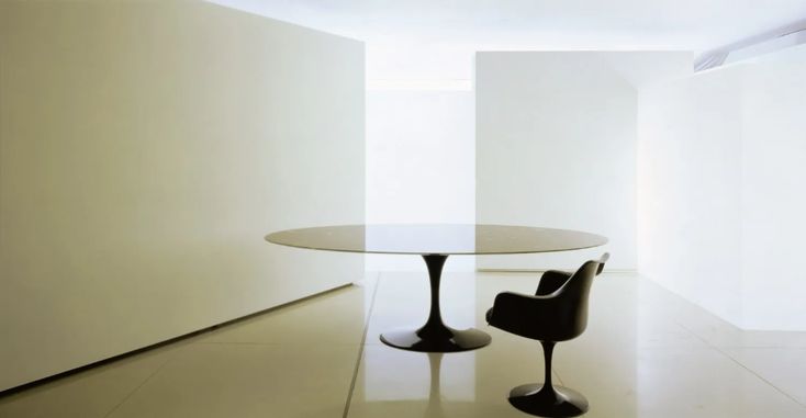 an empty room with a round table and two chairs in front of the wall,