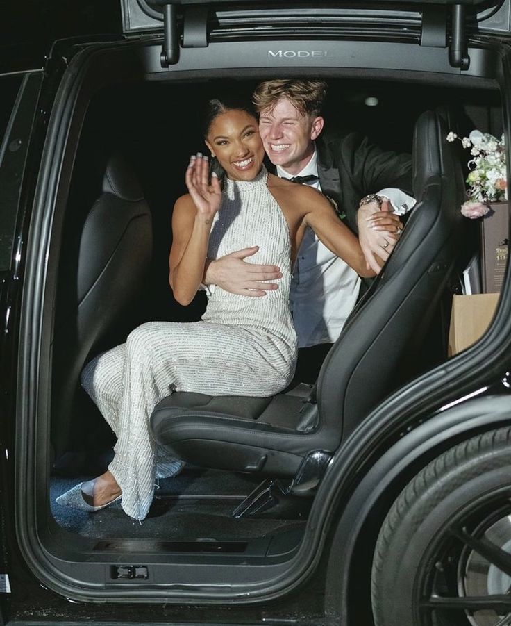 a man and woman are sitting in the back of a car with their arms around each other