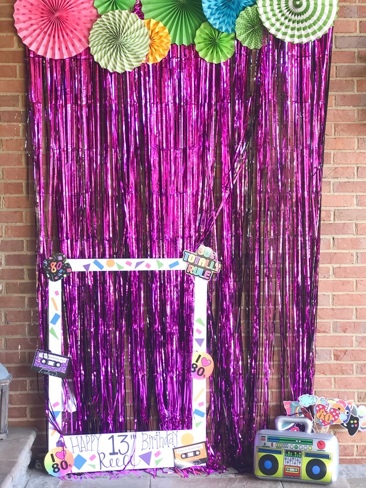 a photo frame with some paper fans hanging from it's side next to a purple curtain