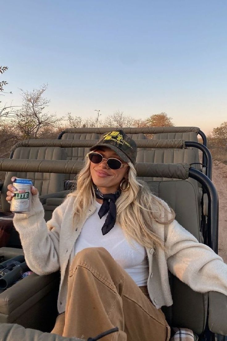 a woman sitting in the back of a truck holding up a can