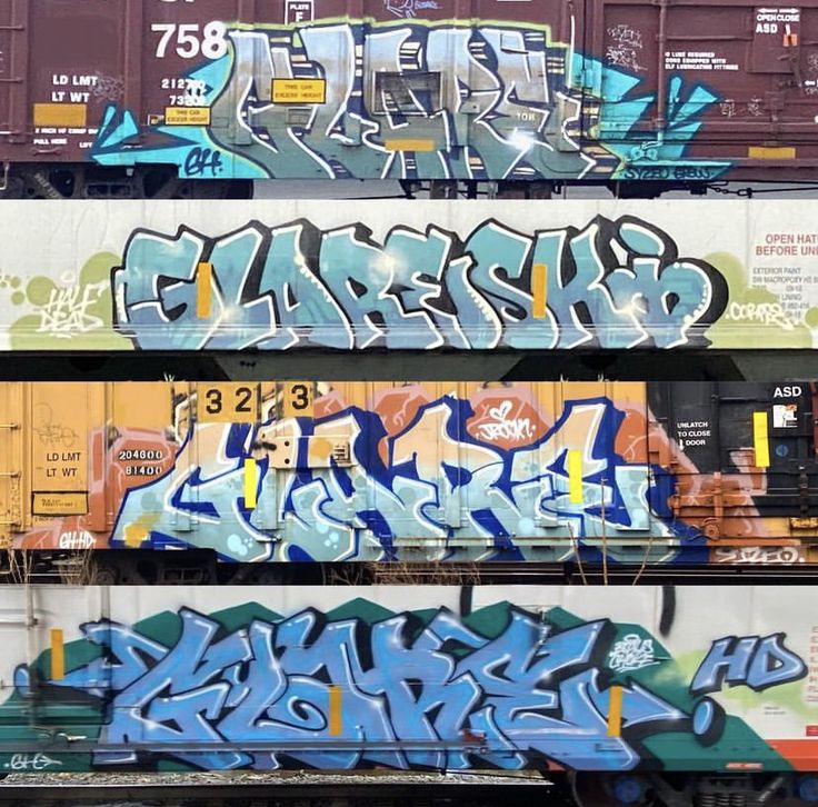 graffiti on the side of train cars in an industrial area with multiple colors and sizes