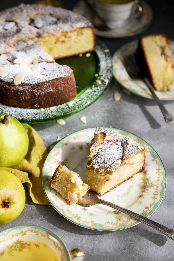 a table topped with plates and cakes covered in powdered sugar next to pears