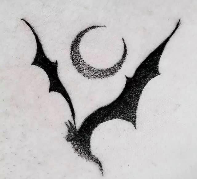 a bat and crescent tattoo on someone's stomach