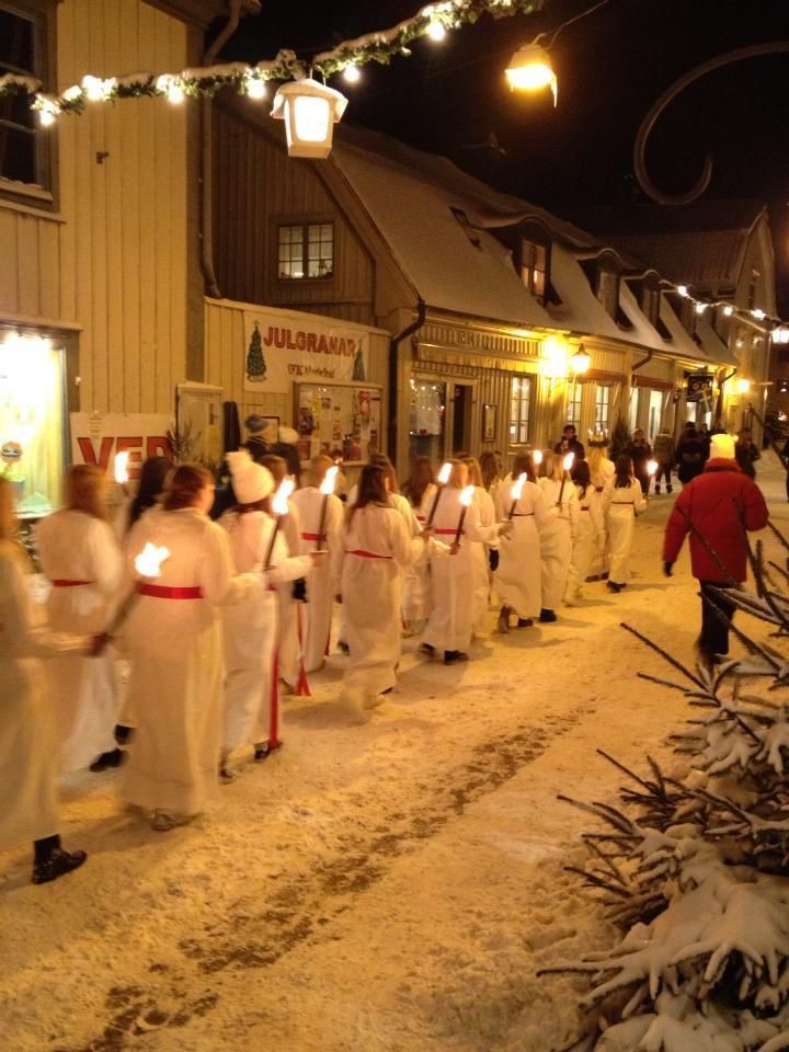 a group of people dressed in white are walking down the street with lit candles on their hands