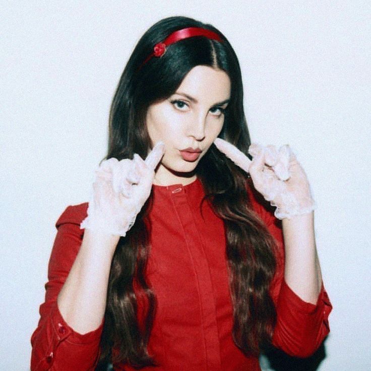 a woman with long dark hair wearing white gloves and holding her fingers up in the air