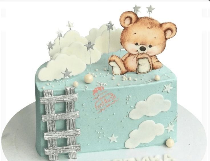 a teddy bear is sitting on top of a blue cake with stars and clouds around it