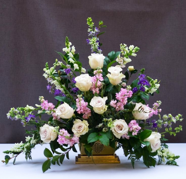 a vase filled with lots of white and pink flowers on top of a wooden stand