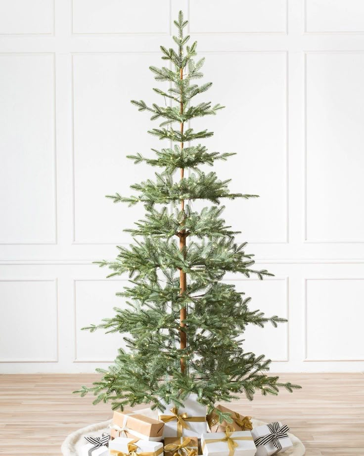 a small christmas tree sitting on top of a white plate with presents under the tree