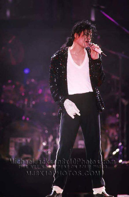 michael jackson performing on stage with microphone in his hand and other instruments behind him as he sings