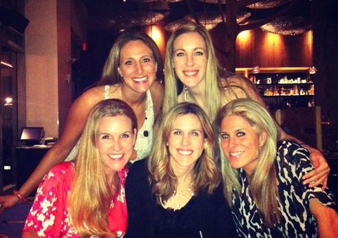 a group of women sitting next to each other posing for a photo in front of a bar