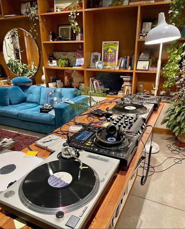 a living room filled with lots of furniture and dj equipment on top of a wooden table