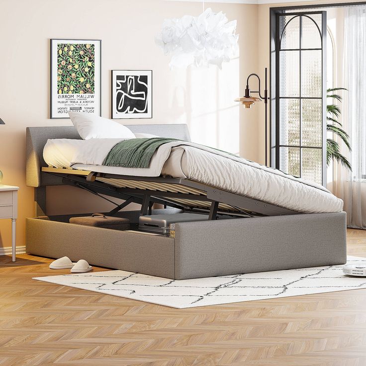 a bed sitting on top of a wooden floor next to a window