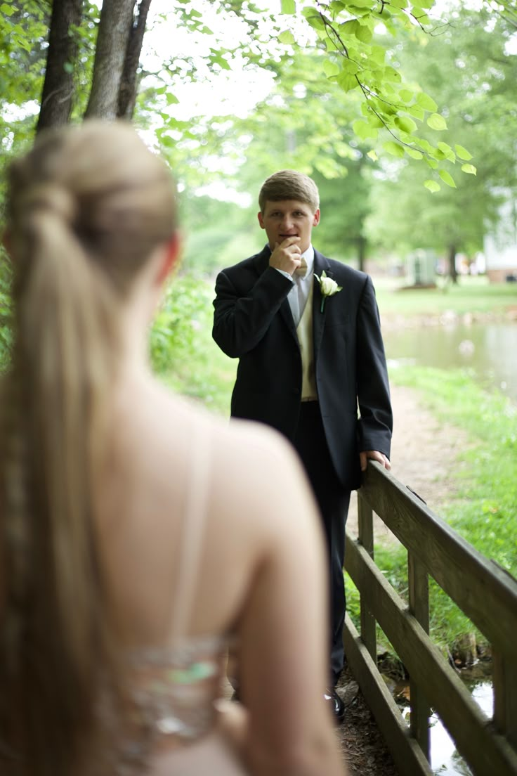 a man in a suit and tie standing on a wooden bridge next to a woman