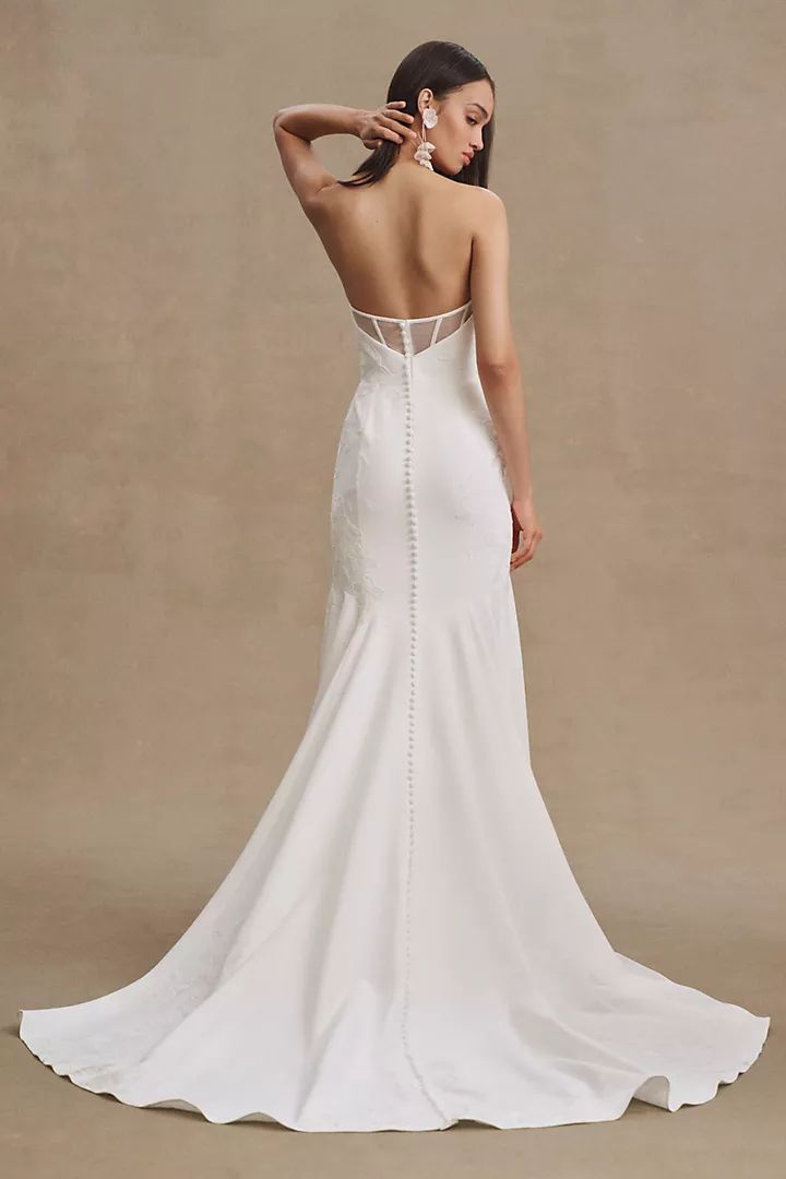 a woman in a white wedding dress is looking down at the back of her gown