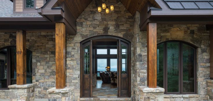 the front entrance to a house with stone walls and doors, windows, and columns