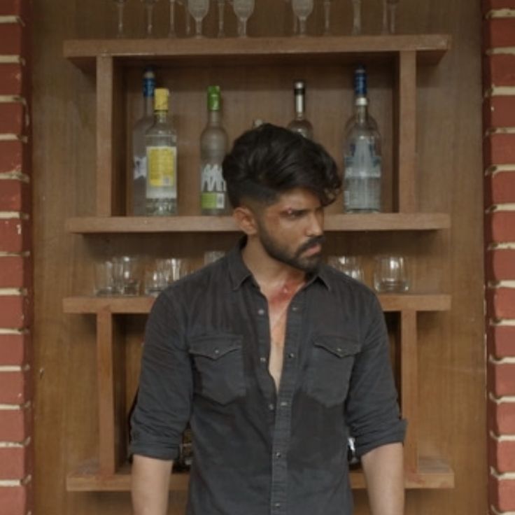 a man standing in front of a shelf with bottles