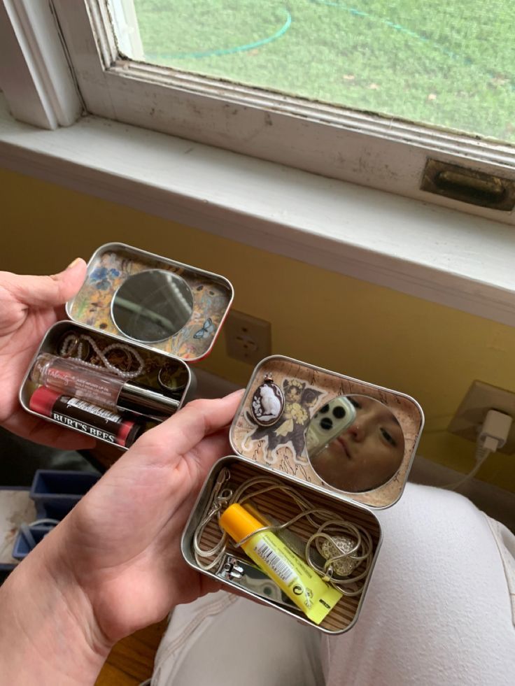 a person holding two tins with various items inside