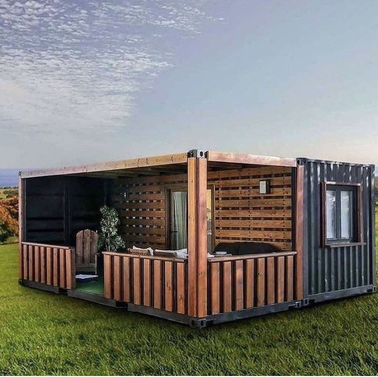 a small house made out of shipping containers sitting on top of a lush green field