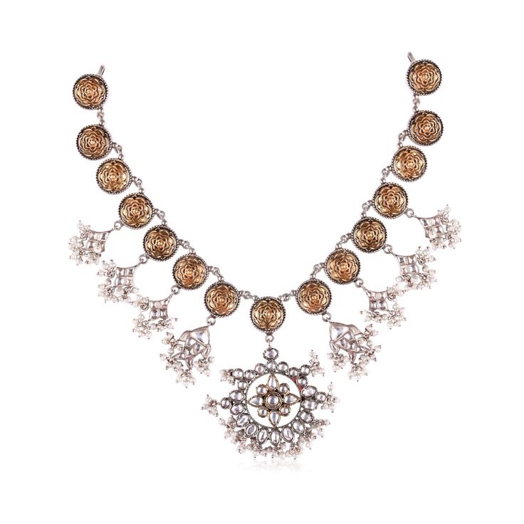 The Niovi Lotus Jadau Necklace features delicate lotus motifs linked together, adorned with beautiful fish charms encrusted with semi-precious polkis. The necklace also showcases a stunning main pendant made with polki and jadau setting. The two-tone antique finish with pearl hangings adds a touch of vintage charm, making it a perfect complement to any ethnic or fusion outfit. Festive Kundan Necklace With Filigree, Festive Kundan Necklace With Filigree Details, Festive Kundan Filigree Necklaces, Festive Kundan Filigree Necklace, Elegant Festive Metal Temple Necklace, Filigree Kundan Jewelry For Celebration, Festive Round Jeweled Necklaces, Temple Jewelry Kundan Filigree Necklace, Kundan Filigree Temple Jewelry Necklace