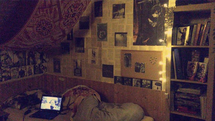 a laptop computer sitting on top of a bed in a room filled with books and pictures