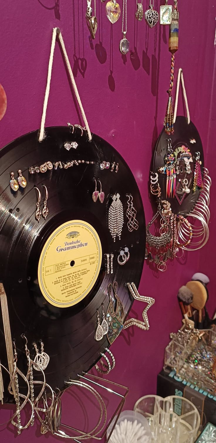 an old record with jewelry hanging from it's sides on a purple wall next to other items