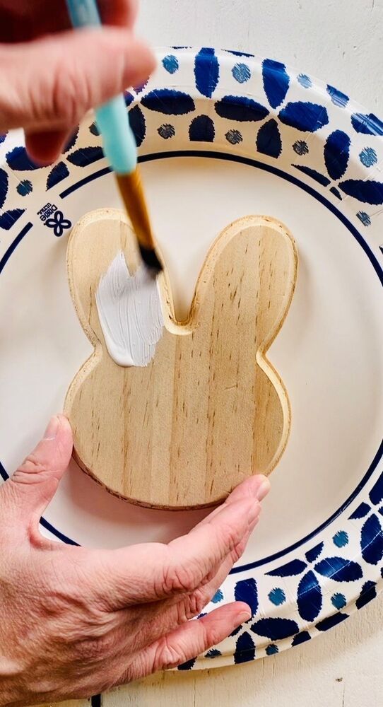 a person is painting a wooden bunny on a plate