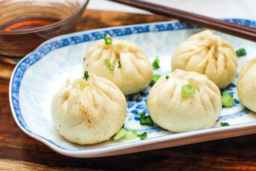 some dumplings are sitting on a blue and white plate with chopsticks next to it