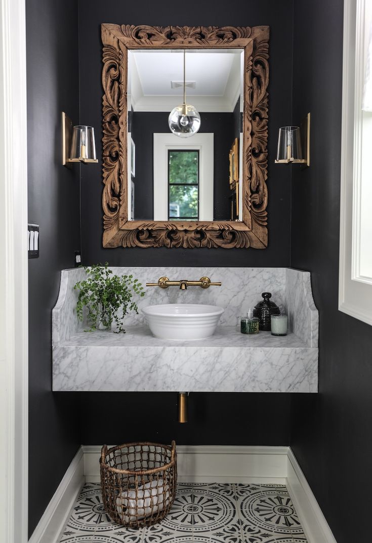 a white sink sitting under a bathroom mirror next to a wooden basket filled with flowers