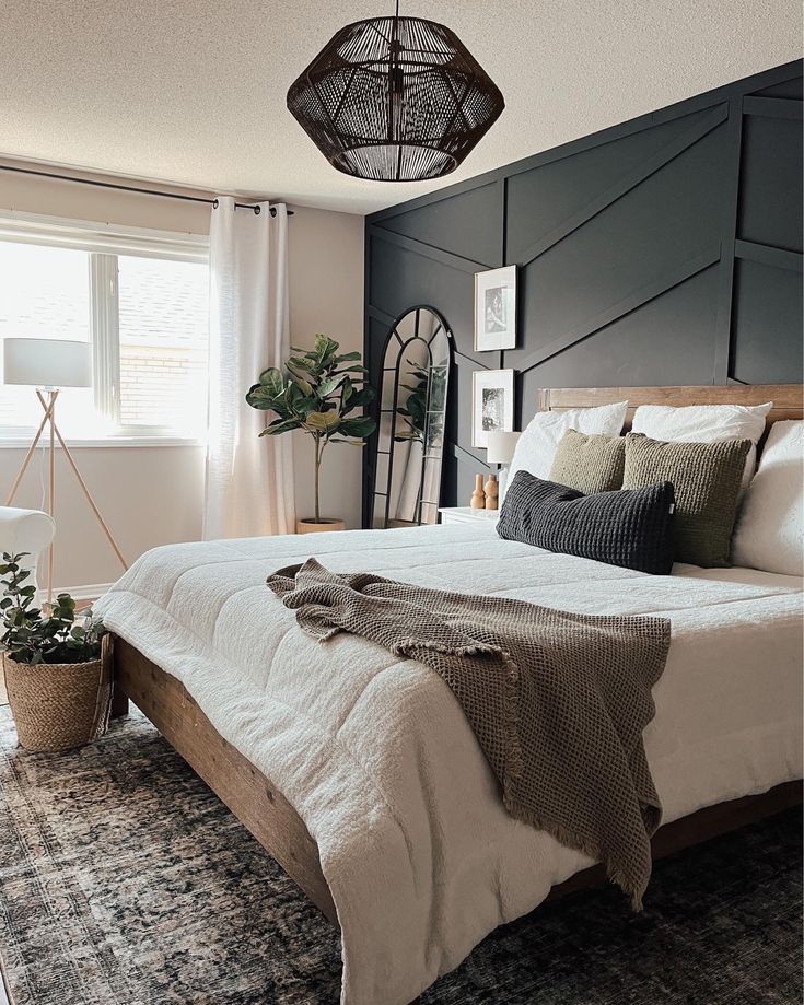 a bedroom with a large bed and black accent wall behind the headboard, along with potted plants