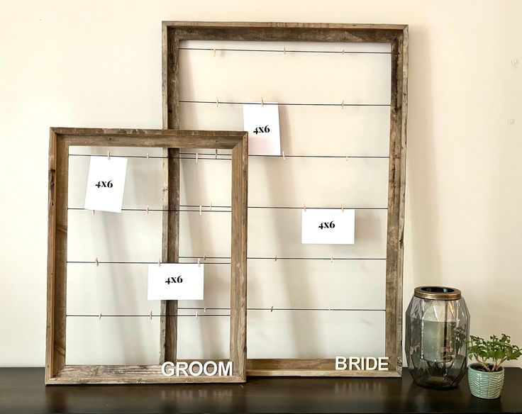 two wooden frames sitting on top of a table next to a vase filled with flowers