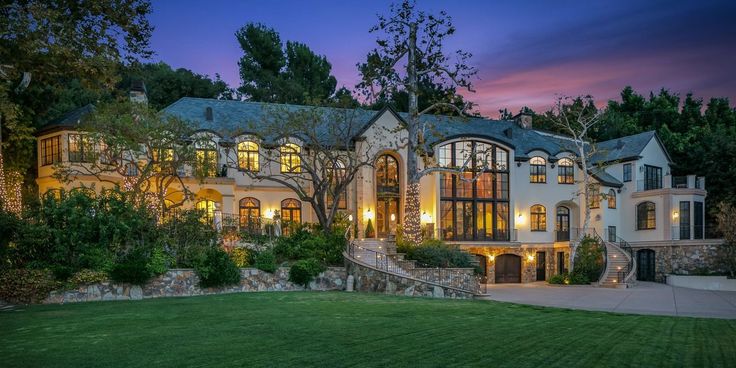 a large house with lots of windows and lights on it's front lawn at night