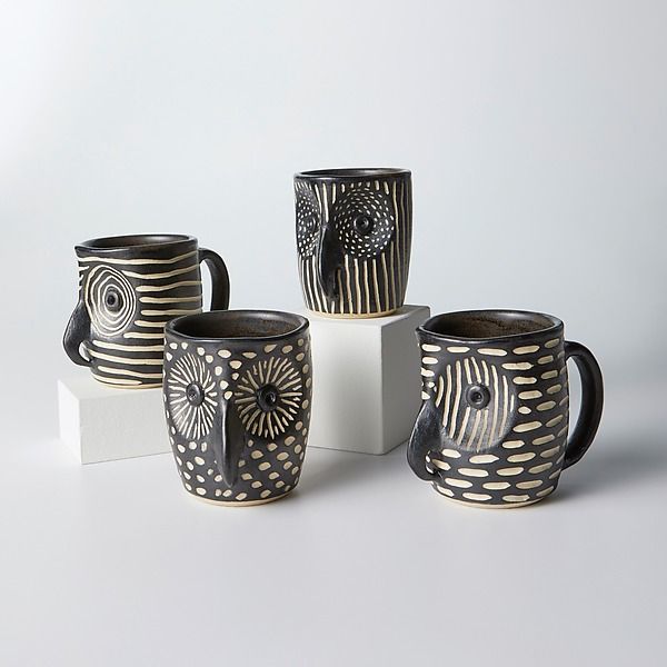 four black and white coffee mugs sitting next to each other on top of a table