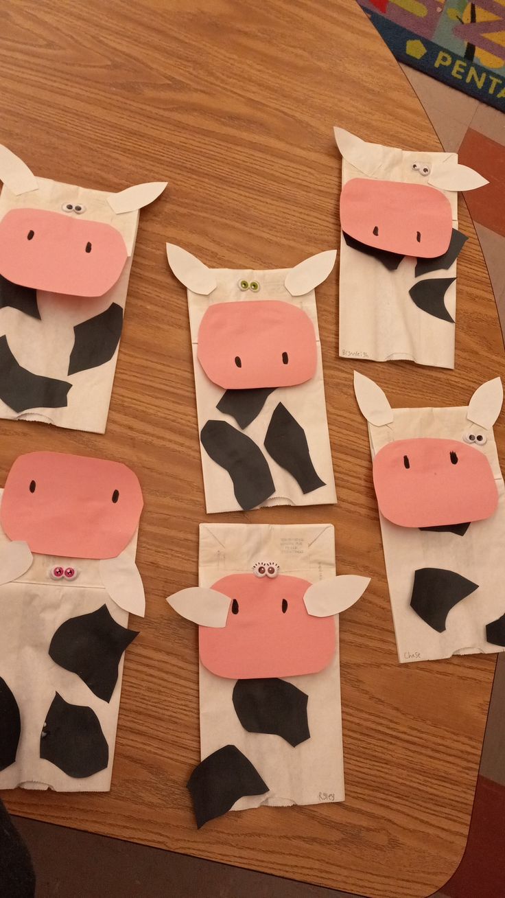 some paper bags with cows cut out of them on top of a wooden table,